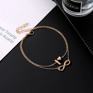 Double-layered gold anklet with heart, bar, and infinity charms on a minimal background