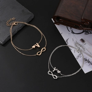 Detail of double-layer ankle bracelets with heart, infinity symbols and alphabet charms