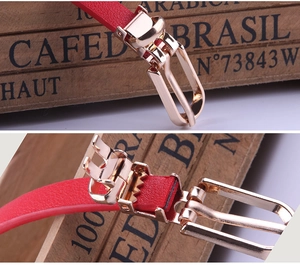 Detail of red PU leather belt with golden metal buckle showing functional gear mechanism