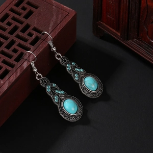 Gros plan de boucles d'oreilles vintage en turquoise sur un cadre en bois rouge sculpté