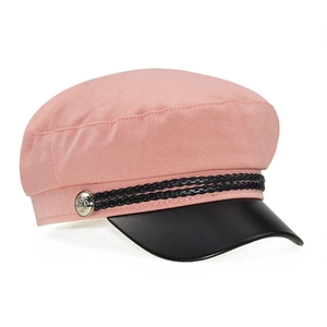 Detail of pink newsboy cap with black leather brim and silver embossed metal buttons