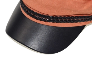 Detail of a vintage baker boy hat featuring an orange fabric crown and black faux leather brim