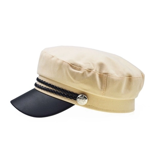 Detail of stylish contrast navy hat with beige crown, black brim, and braided cord accent
