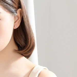 Minimalist golden sphere stud earring shown in a close-up side view on model
