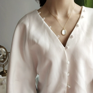 Detail shot of a vintage 925 silver gold oval necklace with white shell inlay on a model