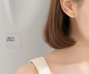 Minimalist round gold stud earring shown as a real effect on a model's earlobe