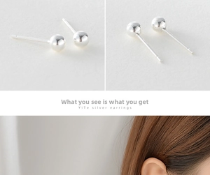 Close-up of polished silver ball stud earrings with detailed side views and ear model shot