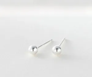 Close-up of minimalist polished sterling silver ball stud earrings with pin backs