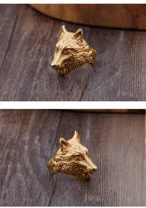 Detailed views of a textured gold wolf head ring on a rustic wood background