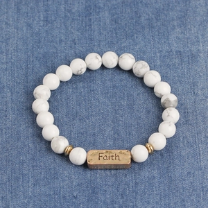 Detailed macro view of white marble beads bracelet with gold spacers and Faith metal plate