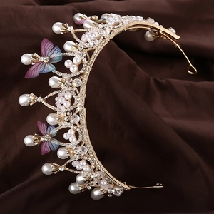 Detailed macro of golden butterfly crown with pearls and crystals on velvet surface