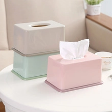 Detailed view of cream, mint green, and pink rectangular tissue boxes on a white table