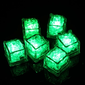 Set of six glowing green LED ice cubes made of clear plastic on a dark reflective surface