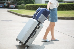 Foldable travel duffel bag in blue and grey attached to a silver suitcase trolley handle