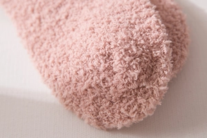Macro shot of pink coral fleece socks showing soft plush texture and warm material details