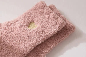 Close-up of pink coral fleece socks with gold heart embroidery showing soft texture