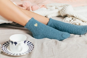 Cozy blue coral fleece sleep socks featuring heart embroidery in a warm lifestyle setting