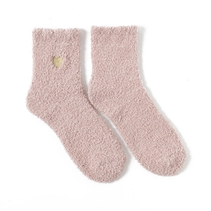 Detail showing soft pink coral fleece fabric and golden heart embroidery on the cozy socks