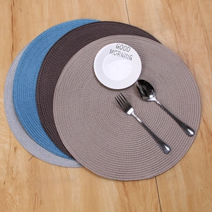 European round woven placemats in four colors with dish and silver cutlery on wood surface