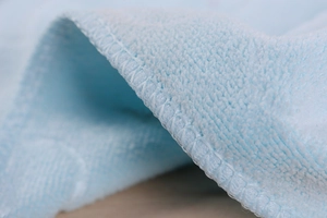 Macro shot of light blue microfiber towel showing reinforced edges and soft plush texture