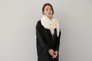 Close-up of cream white cashmere feel knit scarf with elegant fringe detail on model