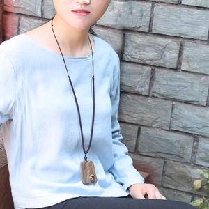 Ethnic vintage wooden pendant necklace with woven cord shown on a model against a wall