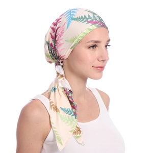 Detail of female turban hat featuring vibrant fern plant prints on beige silky fabric