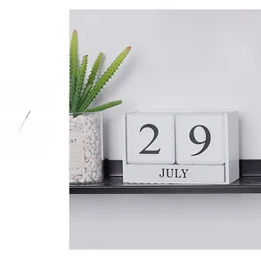 Detail of wooden perpetual calendar showing date on a black shelf with cactus