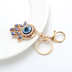 Detailed view of golden Hamsa keychain with blue evil eye beads and crystal rhinestones