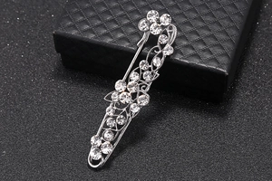 Detailed close-up of a silver brooch with sparkling rhinestones on a black jewelry box