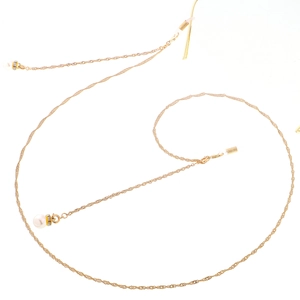 Detailed macro view of golden metal eyeglass chain with white pearl accents and dual clasps