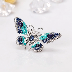Elegant butterfly brooch with blue enamel and rhinestones on white reflective surface