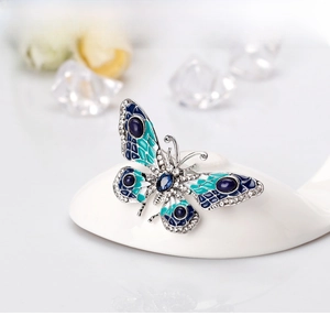Detailed close-up of a blue enamel butterfly brooch with crystals on a white pedestal