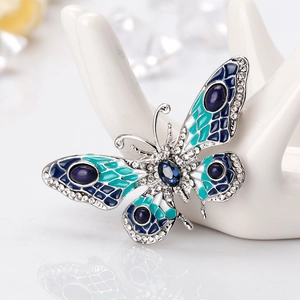 Elegant blue butterfly brooch with rhinestones and enamel on a ceramic display