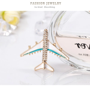 Close-up of golden aircraft brooch with sparkling crystals and white enamel finish