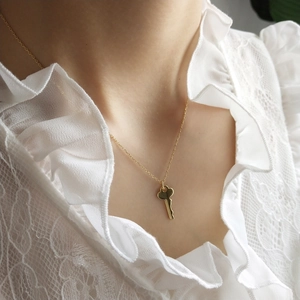 Close-up of a golden heart key pendant necklace on a delicate chain with lace