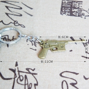 Detail view of a vintage bronze metal pistol keychain with C96 Mauser engraving