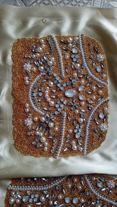 Close-up of intricate gold beadwork and clear rhinestone embroidery on a luxury evening bag