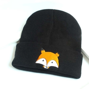 Gros plan du bonnet noir en tricot avec broderie de renard orange sur le revers plié