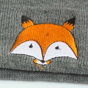 Gros plan d'un bonnet en tricot gris pour bébé avec broderie de renard détaillée