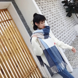 Close-up of blue and beige checkered knit scarf with long tassels and soft texture