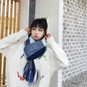 Detailed view of blue and white plaid cashmere-like scarf with fringe on model