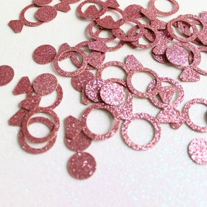 Macro shot of pink glitter graduation party confetti in ring dot and candy shapes