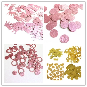Close-up of glitter crown, ring, and heart-shaped graduation table confetti in rose gold