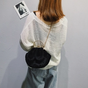 Cloud-shaped black plush handbag with gold ring handle and chain on a stylish model