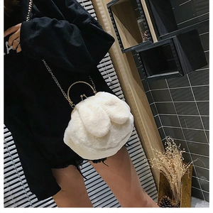Detailed view of a white plush rabbit bag featuring a gold chain and handle on a model