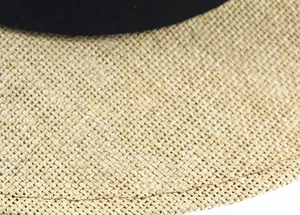 Close-up of tightly woven natural straw texture and black decorative ribbon on sun hat