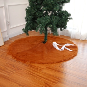 Close-up of brown faux fur Christmas tree skirt on wood floor with white ribbons