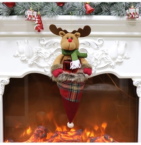 Detail of reindeer Christmas gift bag with plaid pattern hanging by a warm fireplace