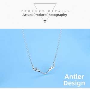 Detailed view of silver elk antler pendant necklace with delicate chain on blue background